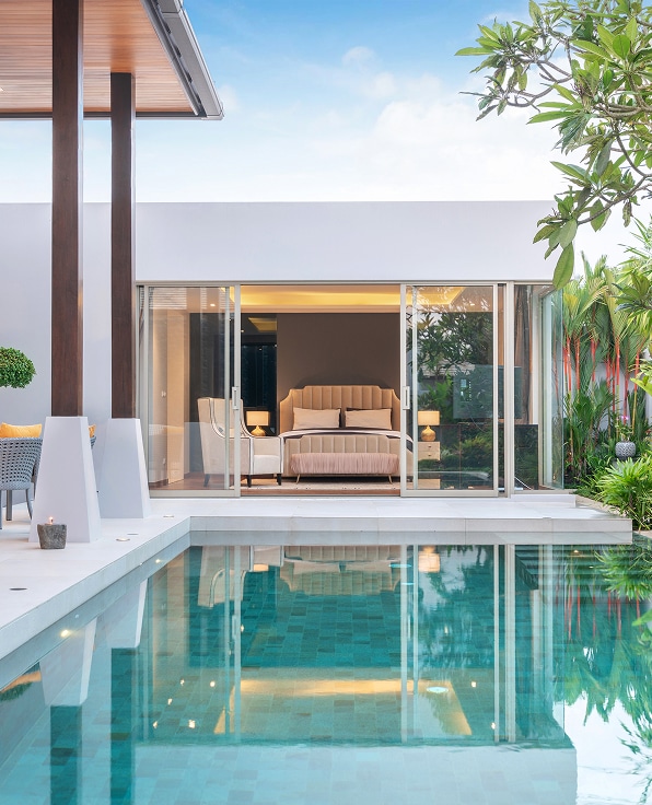 Villa de Luxe: Piscine Privée & Suite Moderne Éblouissante Chambre de villa luxueuse et moderne avec lit double, ouverte sur une piscine turquoise scintillante et une terrasse verdoyante.