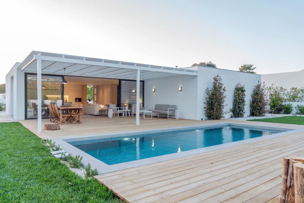 Design Extérieur : Maison Moderne, Piscine & Terrasse Bois Maison moderne avec piscine, grande terrasse en bois, et pergola. Coin repas et salon extérieur. Jardin verdoyant attenant.