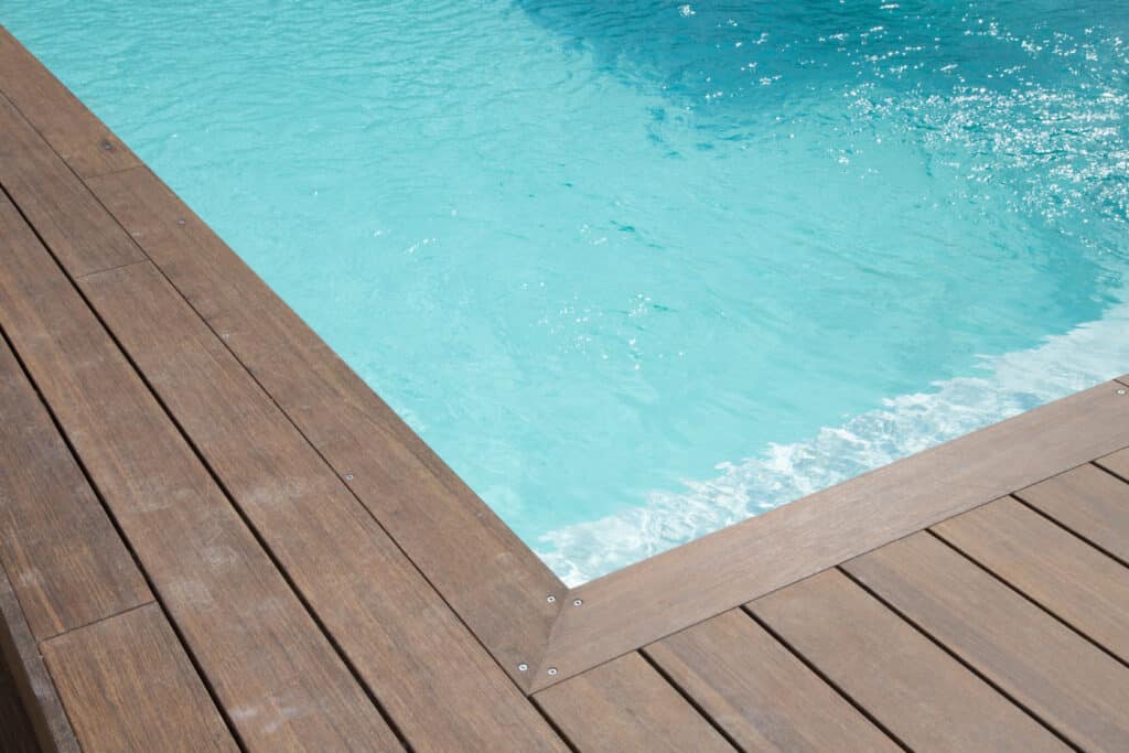 Piscine et Terrasse Bois : Rafraîchissement garanti Piscine moderne à l'eau turquoise scintillante, bordée par une terrasse en bois foncé. Reflets de soleil sur l'eau claire.